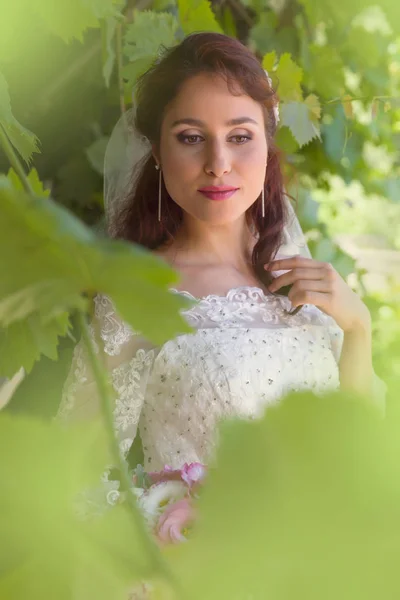 Beautiful bride in green foliage — Stock Photo, Image