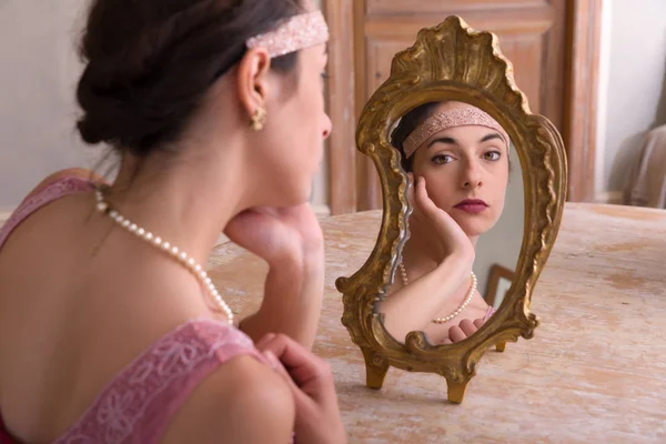 Девушка в платье, смотрящая в зеркало — стоковое фото