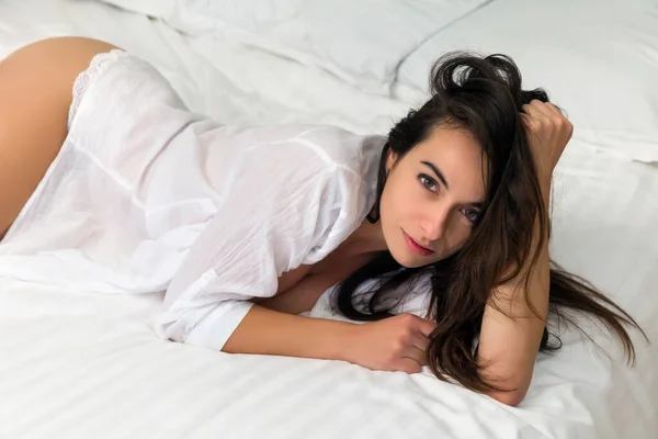 一个性感的年轻女人穿着一件凌乱的白色衬衫 躺在维多利亚时代卧室里一张古旧的天篷床上 — 图库照片