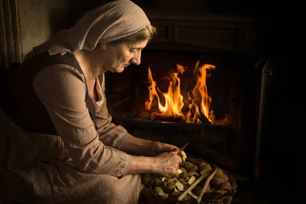 文艺复兴时期一位农妇在壁炉前剥皮马铃薯的画像 — 图库照片