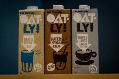 Antwerp, Belçika, Ekim 2019 - Illustrative Editorial: Koyu bir arka planda üç paket Oatly bitkisel ve vegan sütü, hafer, kakao ve barista