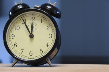 Antika ve antika analog alarm saati, koyu mavi arka planda saat sabahın 5 'i ya da 5' i olduğunu gösteriyor.