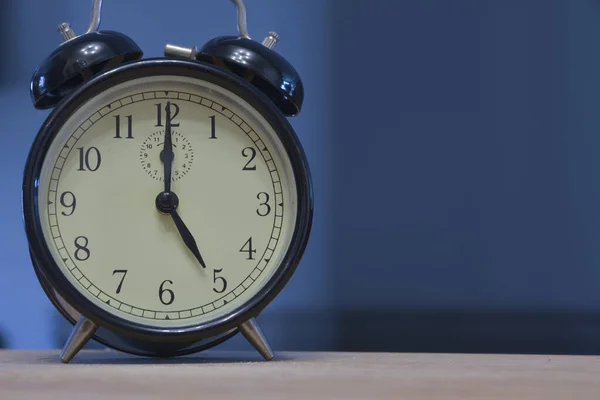 Antika ve antika analog alarm saati, koyu mavi arka planda saat sabahın 5 'i ya da 5' i olduğunu gösteriyor.