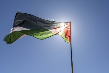 Ürdün bayrağı dalgalanır açık mavi gökyüzüne ve güneşe karşı. 