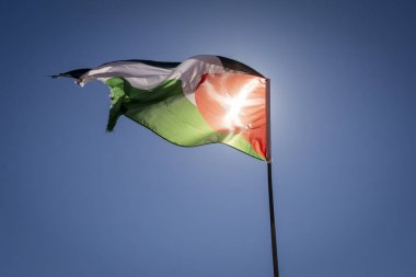 Ürdün bayrağı dalgalanır açık mavi gökyüzüne ve güneşe karşı. 