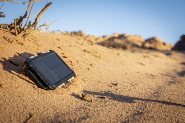 Güneşli bir günde çölün doğasına ve kumuna elektrik yükleyen güneş paneliyle engebeli bir enerji bankası. Gezici aygıtlarınızın şarj edilmesini sağlayan açık hava macerası. 
