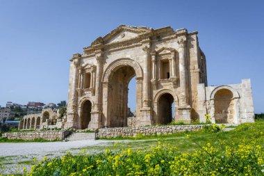 Jerash, Ürdün 'deki Romalı harabelerinde Hadrian kemeri. Mavi gökyüzü olan güneşli bir günde ön manzara. Sergide bazı alışılmadık, muhtemelen Nabataean, akanthus bazları gibi mimari özellikler yer alıyor..