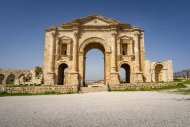 Jerash, Ürdün 'deki Romalı harabelerinde Hadrian kemeri. Mavi gökyüzü olan güneşli bir günde ön manzara. Sergide bazı alışılmadık, muhtemelen Nabataean, akanthus bazları gibi mimari özellikler yer alıyor. Ürdün 'de Seyahat ve Turizm