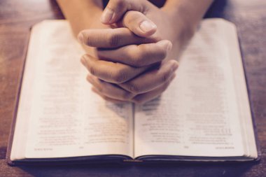 İncil üzerine dua eden eller