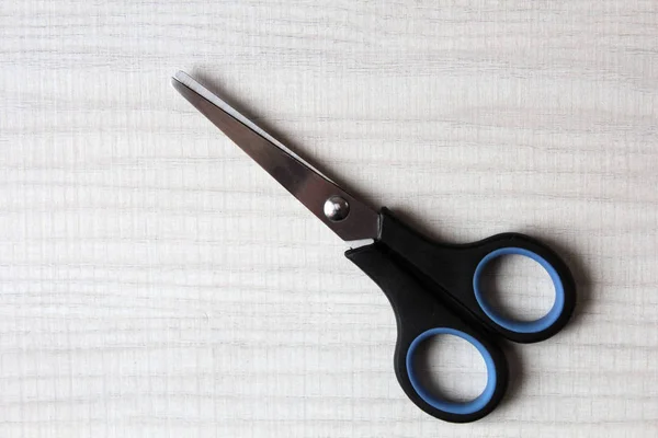 Black scissors lies on white wooden background with copy space — Stock Photo, Image