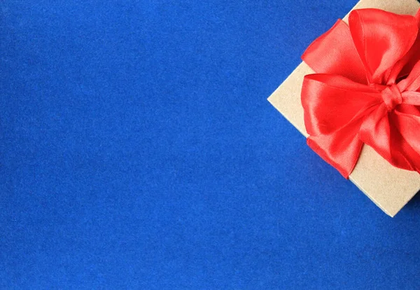 Top view of wrapped  gift box with red ribbon bow on blue backgr — 스톡 사진