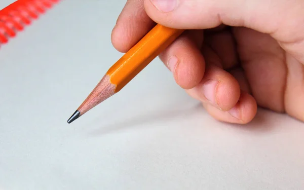Close-up mão criança segurando um lápis no fundo branco . — Fotografia de Stock