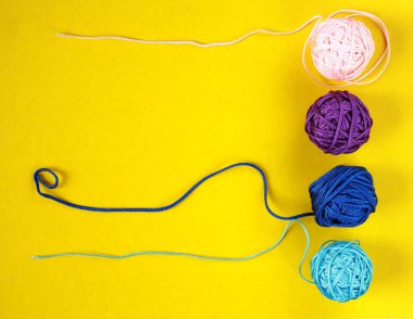 Sarı arka planda renkli naylon iplik toplarının üst görüntüsü. Kalabalıktan ve farklı kavramlardan uzak dur..