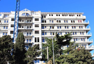 Güneşli yaz gününde mavi gökyüzüne karşı inşaat ve inşaat halindeki çok katlı vinç.