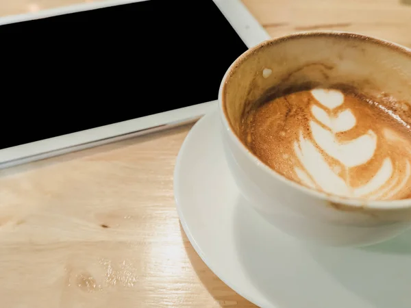 Primer plano taza de café blanco y tableta en escritorio de madera — Foto de Stock