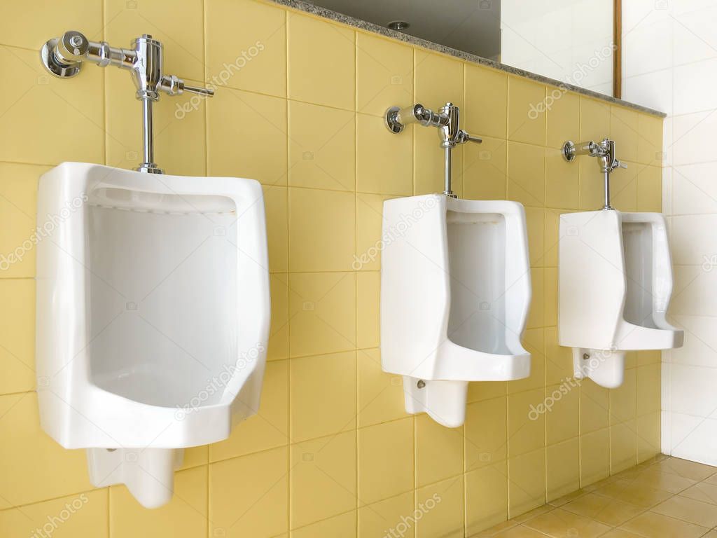 Close up row of outdoor white urinals men on yellow of wall publ