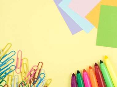 Sarı arka plan üzerinde renkli sihirli kalem ve not kağıtları ve ataş Grup desen