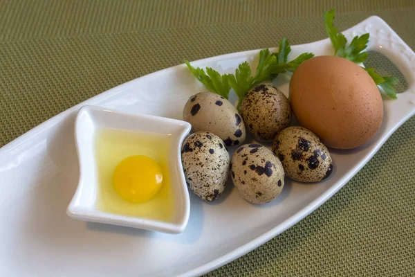 ウズラの卵は 生とロースト 卵とパセリの緑の背景に白皿の上の静物 — ストック写真