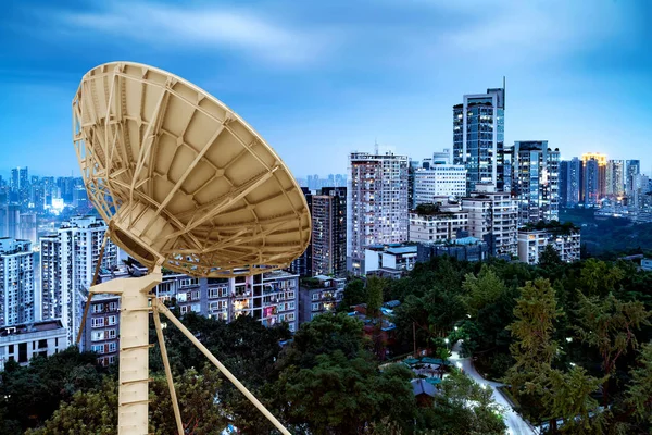 Vista nocturna de la ciudad y antena satelital —  Fotos de Stock