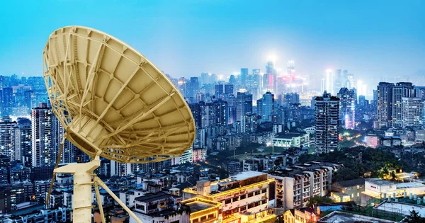 Vista nocturna de la ciudad y antena satelital — Foto de Stock