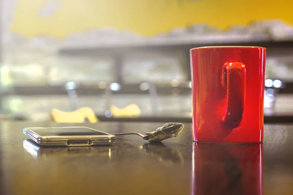 Rode mok met een geperste theezakje op een lepel, met een smartphone op — Stockfoto