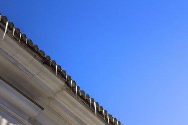 Çatıdaki buz saçakları mavi gökyüzüne karşı