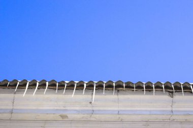 Çatıdaki buz saçakları mavi gökyüzüne karşı