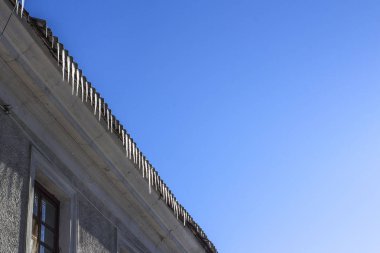 Çatıdaki buz saçakları mavi gökyüzüne karşı