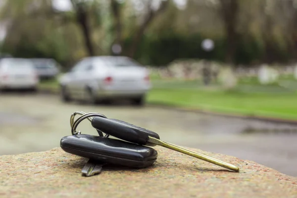 Llaves de coche perdidas en una losa de mármol, en un coche borroso y aparcamiento backgr —  Fotos de Stock