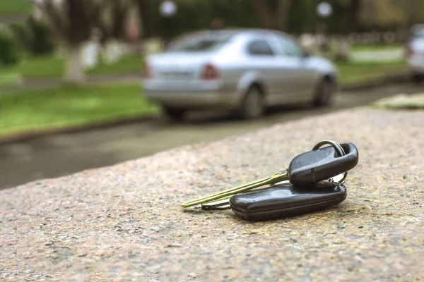 Llaves de coche perdidas en una losa de mármol, en un coche borroso y aparcamiento backgr —  Fotos de Stock