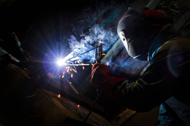 Kaynakçı gece metal işi yapıyor, ön ve arka plan bulanıklaşıyor