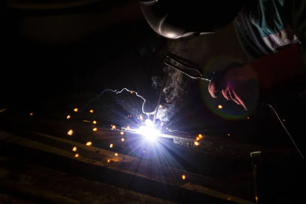 welder doing metal work at night, front and background blurred w
