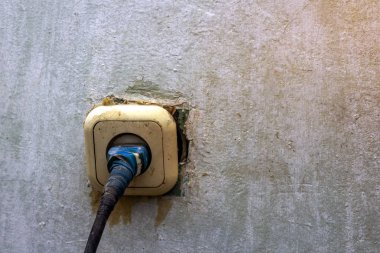Elektrik prizi tamiratında çalışan zavallı yaşlı elektrikçi.