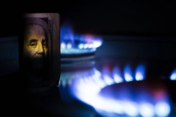 Burning bill of hundred dollars on a gas burner flame, expensive natural gas, the front and background are blurred with a bokeh effect — Stock Photo, Image