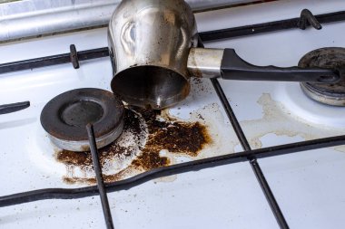 Cezve 'den dökülen kahveyle birlikte kirli gaz sobası.