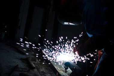 Kaynakçı gece metal işi yapıyor, ön ve arka plan bulanıklaşıyor