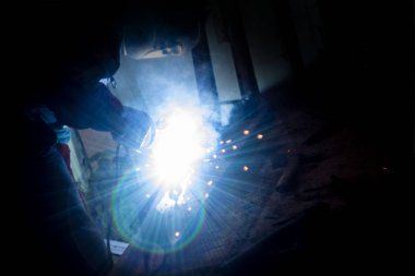 Kaynakçı gece metal işi yapıyor, ön ve arka plan bulanıklaşıyor