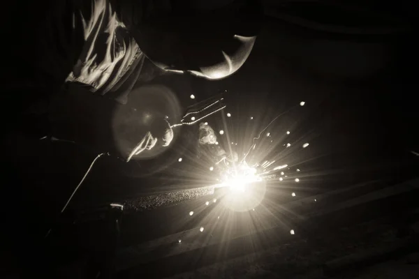 Welder doing metal work at night, front and background blurred w — Stock Photo, Image