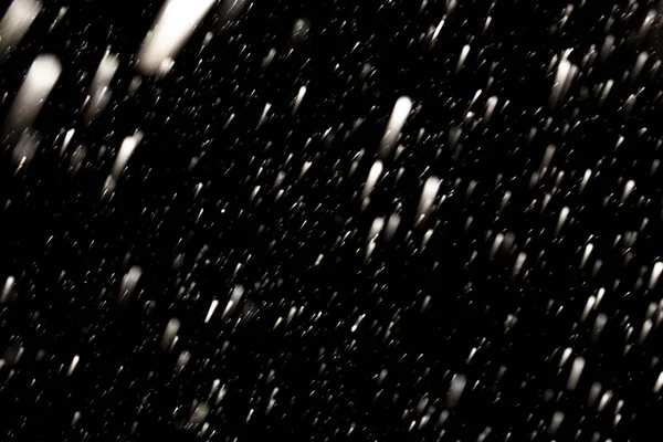 Flakes of snow falling fast against a black sky, the front and b — Stock Photo, Image