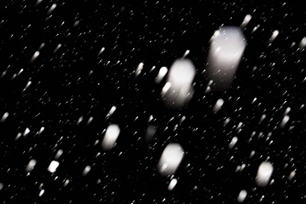 Flakes of snow falling fast against a black sky, the front and b — Stock Photo, Image