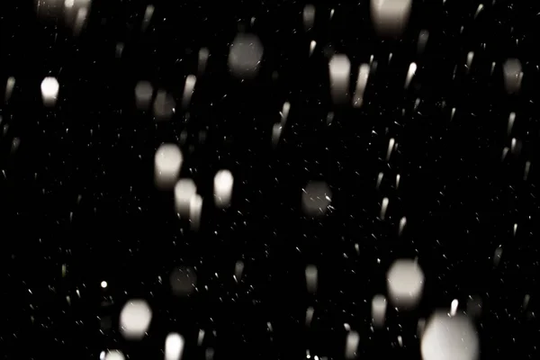 Flakes of snow falling fast against a black sky, the front and b — Stock Photo, Image