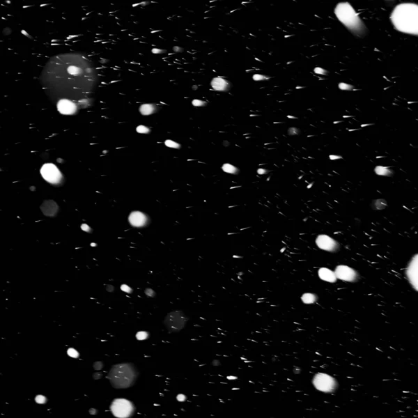 Flakes of snow falling fast against a black sky, the front and b — Stock Photo, Image