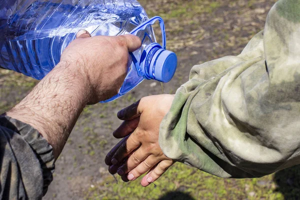 Люди миють руки чистою водою з п'ятилітрової площини — стокове фото