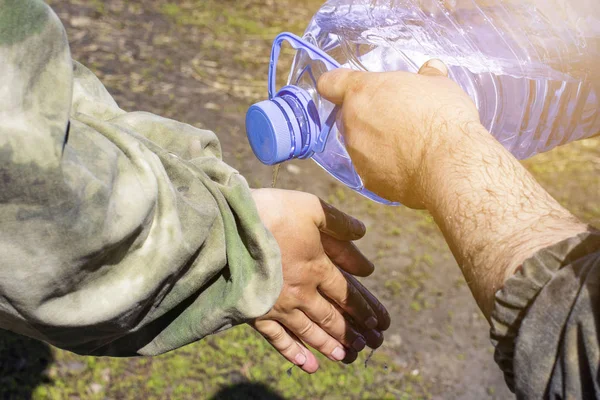 Människor tvättar sina händer med rent vatten från en fem liter pl — Stockfoto