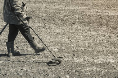 Metal dedektörüyle hazine arayan siyah bir arkeolog.