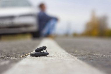 Kayıp araba anahtarları, bulanık bir arka planda yol üzerinde yatıyor.