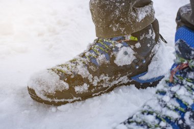 Islak yürüyüş botları kalın taze kar altında, ön ve arka plan bulanıklaşıyor.