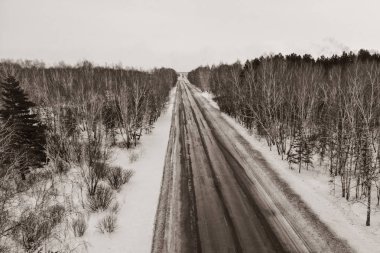 Ormandaki kış yolundaki bir arabanın hava manzarası. Kış manzarası kırsal. Karlı ormanın havadan çekilmiş fotoğrafı ve yolda bir araba var. Yukarıdan bir İHA ile yakalandı.