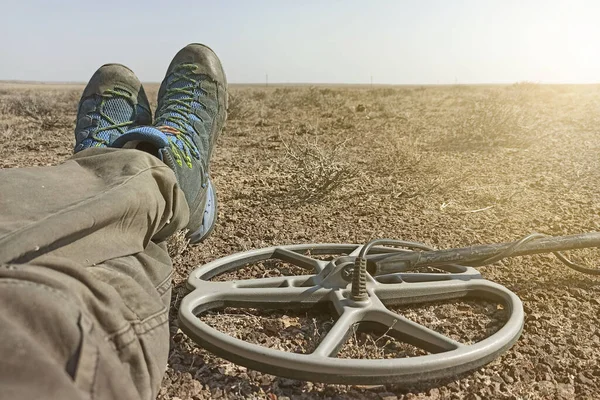 Hazine avcısının geri kalanı bozkırları metal dedektörüyle ararken arka plan bokeh etkisi ile bulanıklaşıyor.