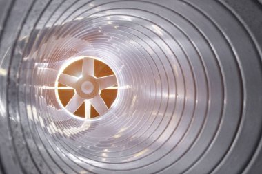 Arka plandaki egzoz vantilatöründeki galvanize çelik hava kanalının içerisinden yakın çekim görüntüsü Bokeh etkisi ile ön ve arka plan bulanıklaşır.